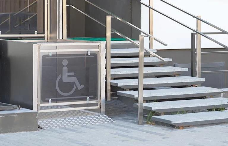 Plattformlift für Rollstühle neben einer Außentreppe am Hauseingang