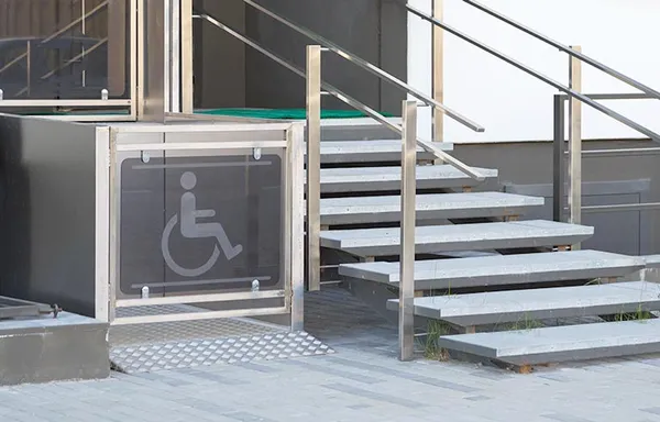 Plattformlift für Rollstühle neben einer Außentreppe am Hauseingang
