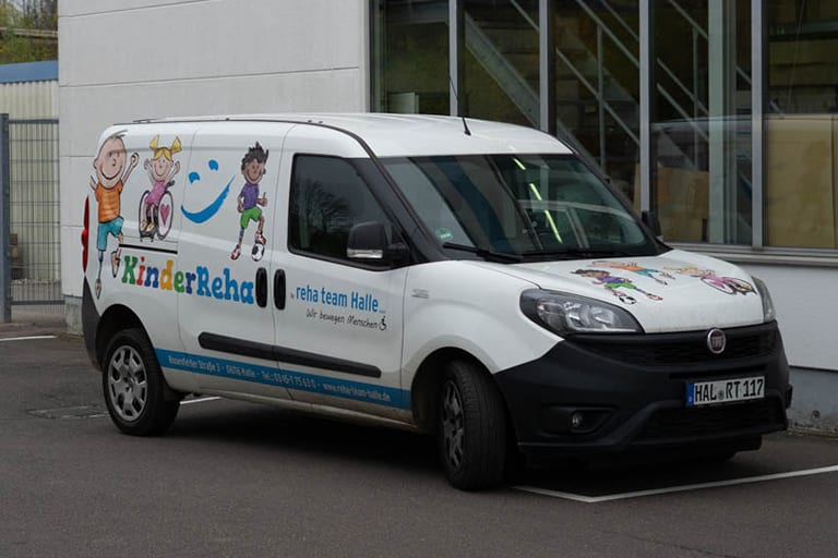 KinderReha-Servicefahrzeug des reha team Halle vor dem Firmengebäude