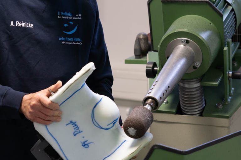 Orthopädietechniker bearbeitet eine Sitzschale in der Werkstatt des reha team Halle